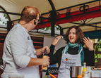 Das Bild zeigt eine Live-Cooking-Szene, bei der die Senatorin Kathrin Moosdorf gemeinsam mit Steffen Rösemeier vom Forum Küche kocht. Die Senatorin trägt eine weiße Kochschürze mit den Logos BioStadt Bremen und Forum Küche. 